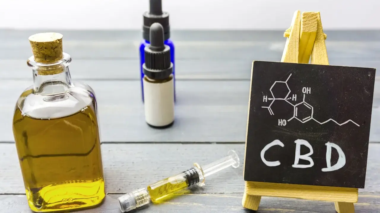 Butelka z olejkiem, strzykawka i tabliczka z napisem CBD. Zastanawiasz się, olejek CBD na co?