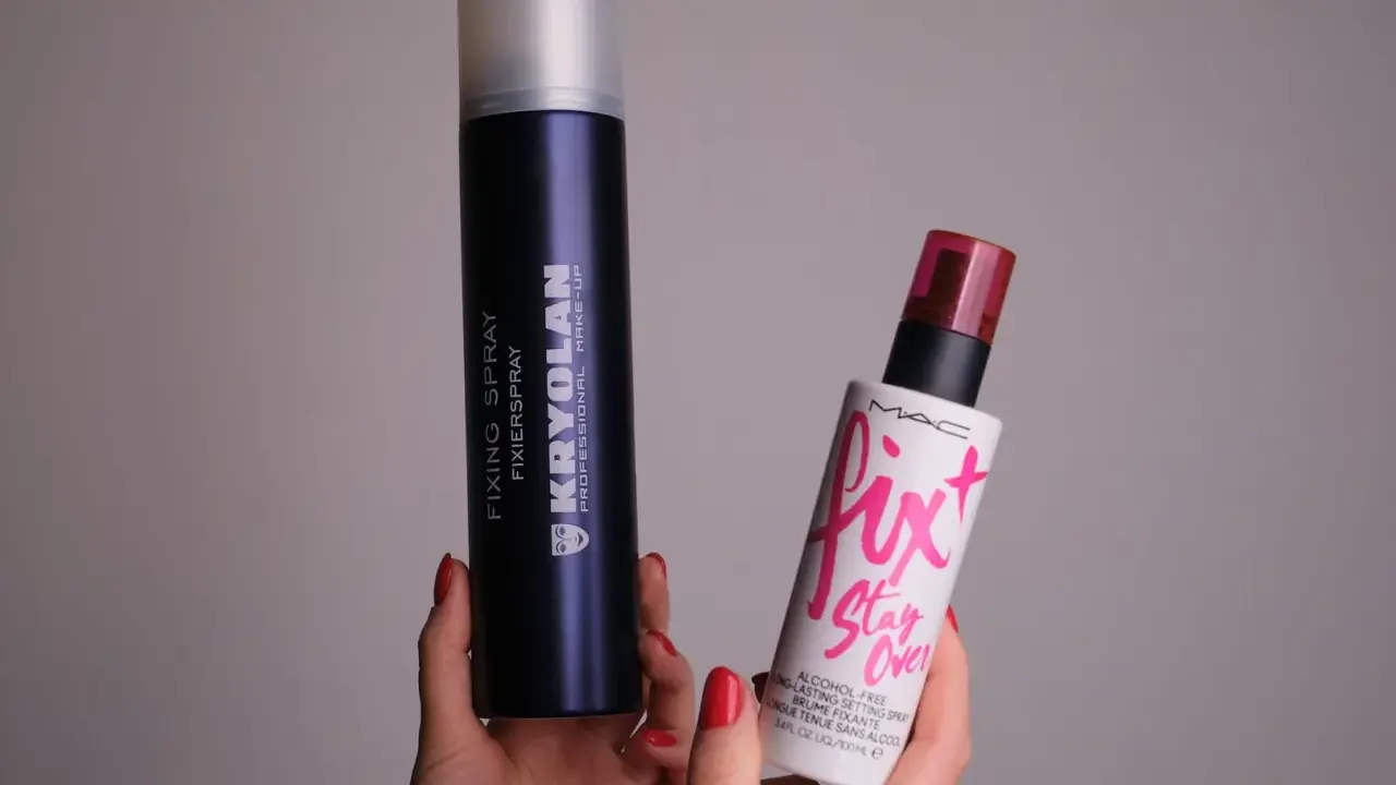 Dwie ręce trzymają dwa spraye: duży, granatowy Kryolan Fixing Spray i mniejszy, biały Fix+ Stay Over MAC. Oba to profesjonalne produkty typu fixer.