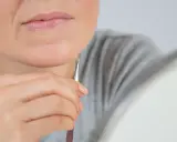 Kobieta wyrywa pęsetą włoski z podbródka.