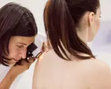 Lekarz od skóry bada znamiona pacjentki dermatoskopem.