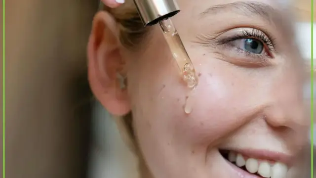 Kropla serum z pipety spada na policzek uśmiechniętej kobiety. Dowiedz się, jak stosować retinol dla pięknej cery.