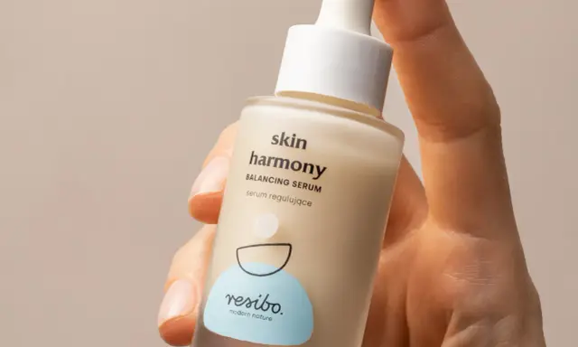 Dłoń trzyma buteleczkę serum Resibo z alantoiną. Skóra harmonijnie odzyskuje równowagę dzięki temu produktowi.