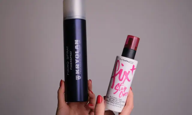 Dwie ręce trzymają dwa spraye: duży, granatowy Kryolan Fixing Spray i mniejszy, biały Fix+ Stay Over MAC. Oba to profesjonalne produkty typu fixer.