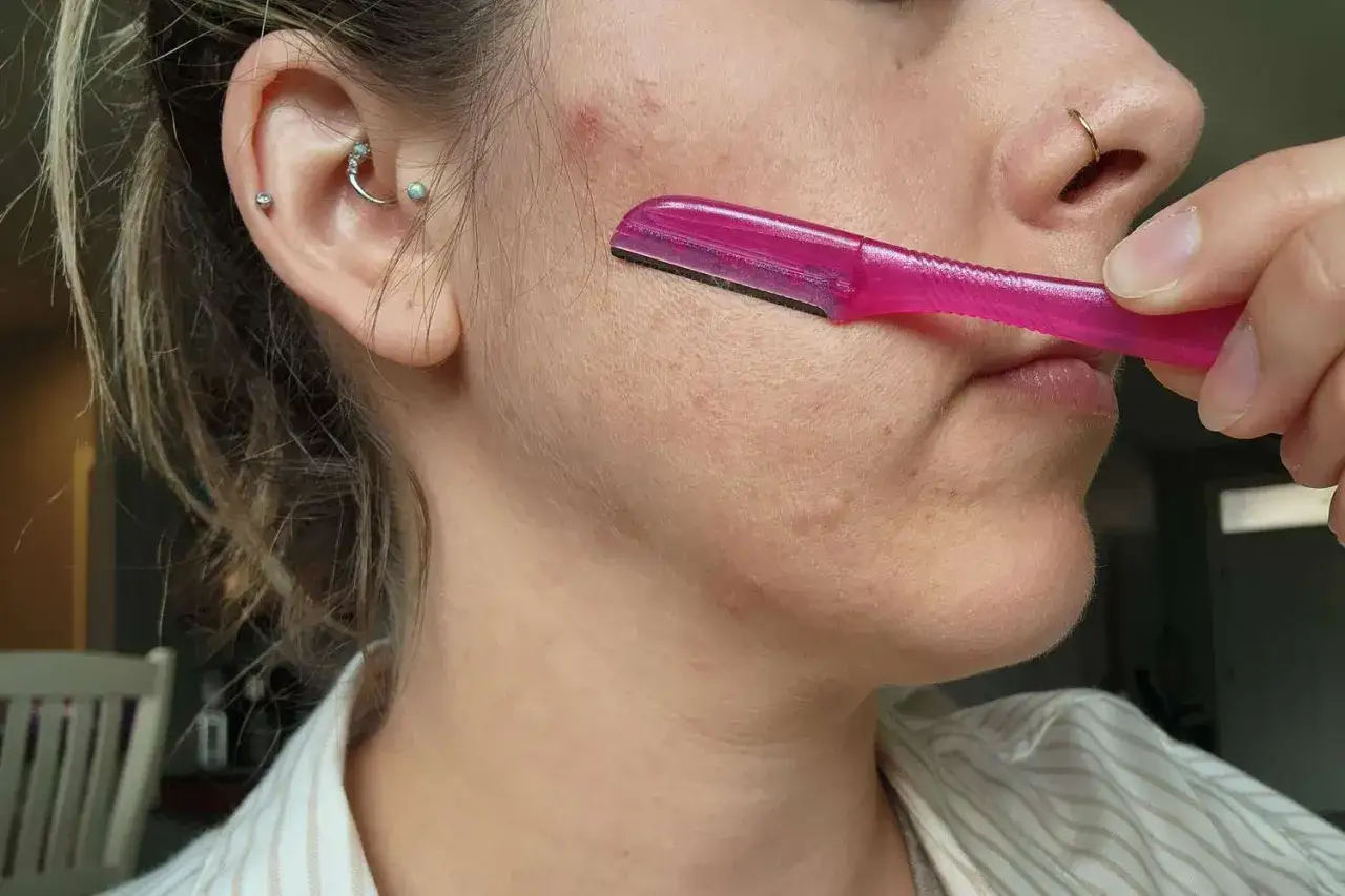 Delikatne usuwanie meszku z twarzy, aby uzyskać gładkość. Różowa maszynka do golenia usuwa peach fuzz.